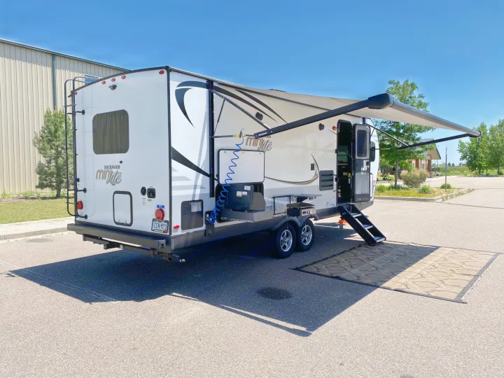 White Rockwood Mini Lite RV rental with extended awning, outdoor kitchen, and large ground mat.. Forest River Rockwood Mini Lite 2021