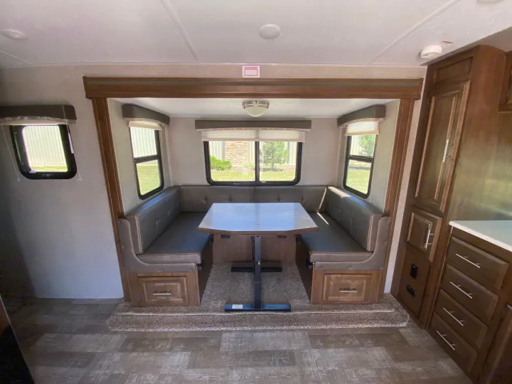 RV rental interior: A spacious U-shaped dinette with comfortable booth seating, large windows, and adjacent kitchen storage.. Forest River Rockwood Mini Lite 2021