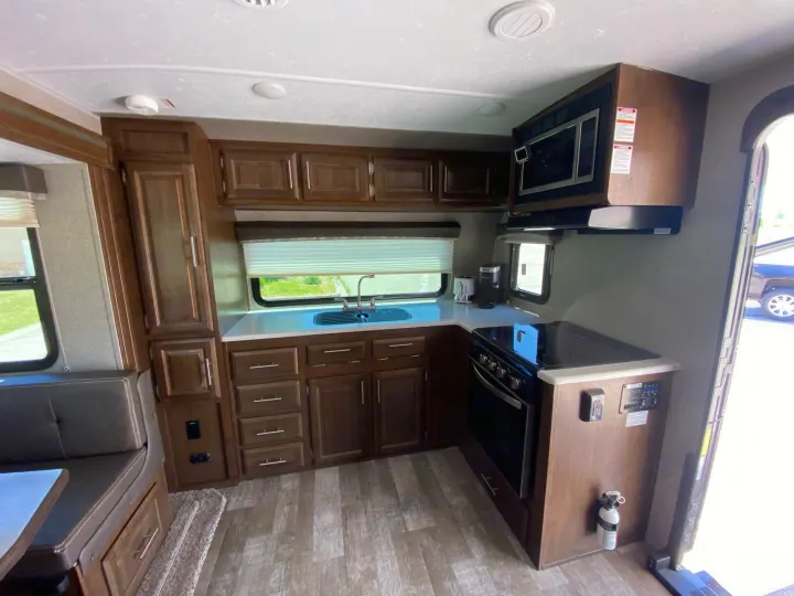 Inside this RV rental: a well-equipped kitchen with sink, stove, microwave, and comfortable dinette seating area.. Forest River Rockwood Mini Lite 2021
