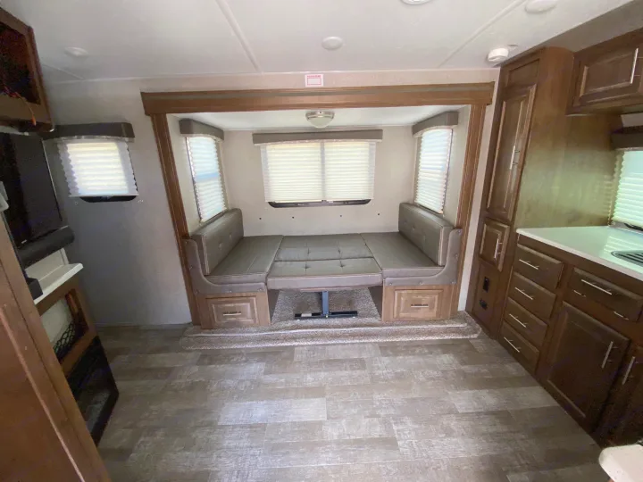 Cozy RV rental interior showing a versatile dinette that converts to a bed, with kitchen counters and storage.. Forest River Rockwood Mini Lite 2021