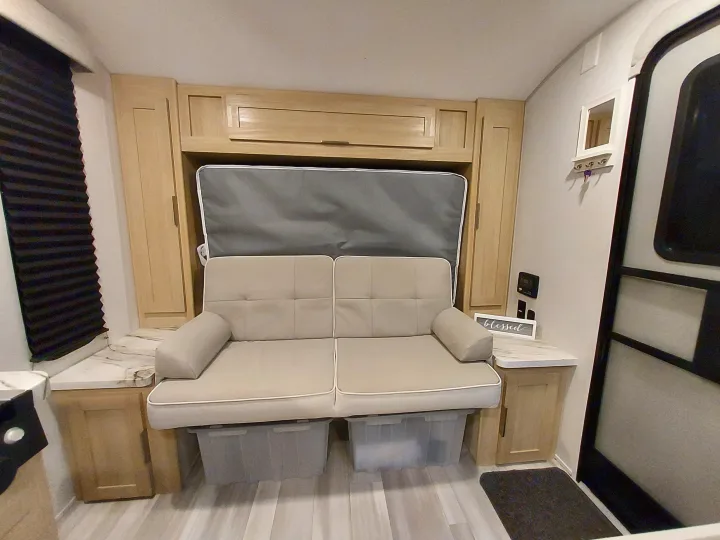 Cozy RV rental interior with convertible sofa, overhead cabinets, window blinds, and organized storage bins, perfect for travel.. Forest River Salem FSX Platinum 2023
