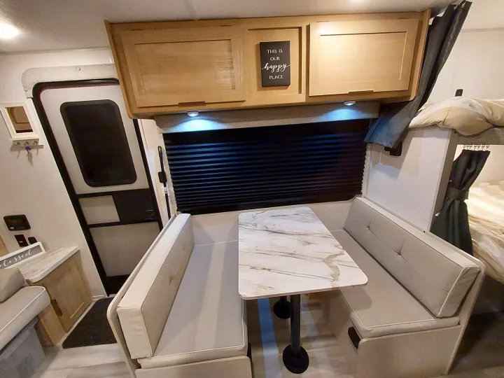 Inside a modern **rv rental**: a compact dinette with light wood cabinets, comfortable benches, and a marble-look table.. Forest River Salem FSX Platinum 2023