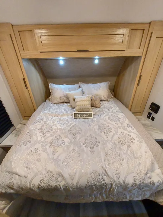 Cozy RV rental bedroom with elegant patterned bedding, built-in wood cabinets, and accent lighting for a comfortable stay.. Forest River Salem FSX Platinum 2023