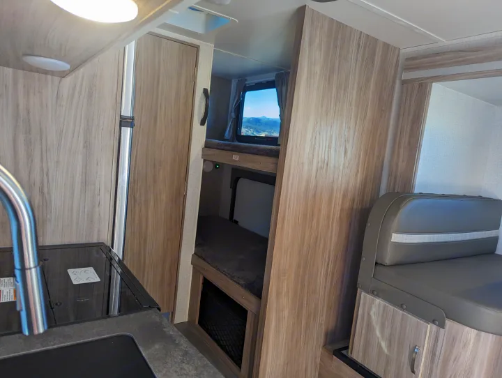 RV rental interior with kitchen, bunk beds, and dinette seating. A window reveals mountain scenery.. Winnebago Micro Minnie 2022