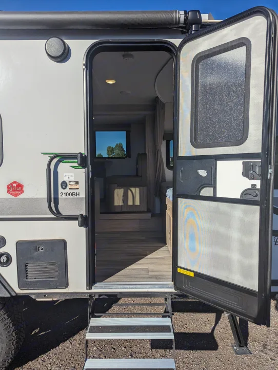 Step into comfort: This rv rental shows its open door revealing a cozy interior, exterior speaker, and convenient entry steps.. Winnebago Micro Minnie 2022