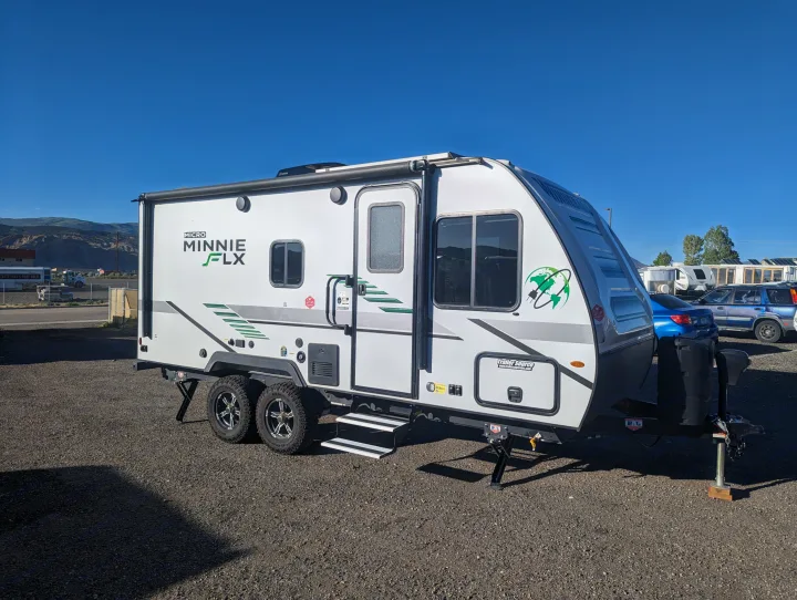 A white Micro Minnie FLX travel trailer, perfect for an RV rental adventure, parked on gravel under a clear sky.. Winnebago Micro Minnie 2022