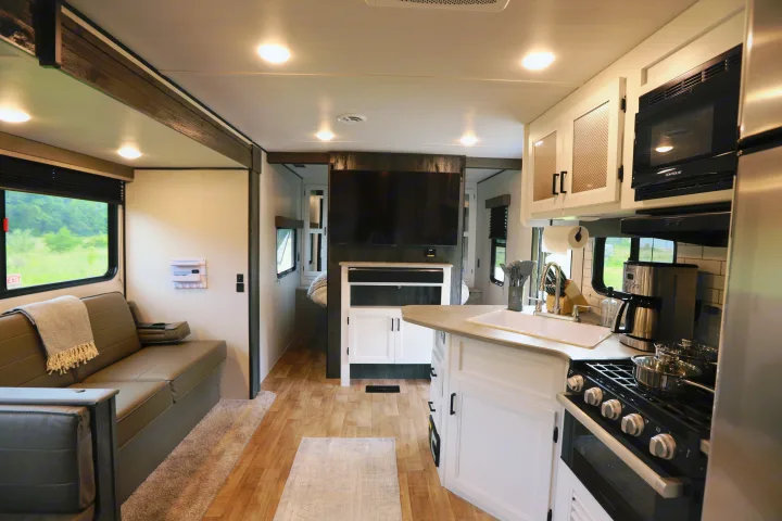 Spacious RV rental interior featuring a full kitchen, comfortable living area with a couch, and a peek into the bedroom.. Keystone RV Hideout 2022