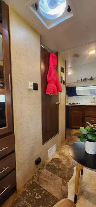Bright RV rental interior: kitchen beyond hallway, pink jacket on door, thermostat, ceiling vent. Ready for your adventure.. Winnebago MicroMini 2306 BHS 2020