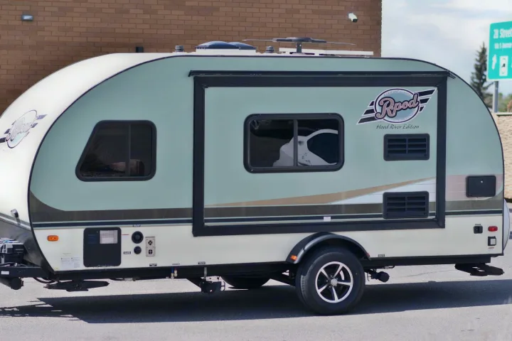 A two-tone Rpod Hood River Edition travel trailer, an rv rental, with an awning and tinted windows, parked outdoors.. Winnebago MicroMini 2306 BHS 2020