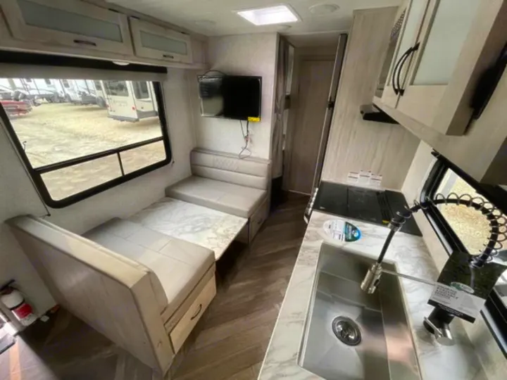 Spacious, modern RV rental interior featuring a dinette, kitchen, and living area, ideal for travel adventures.. East to West Della Terra 2023