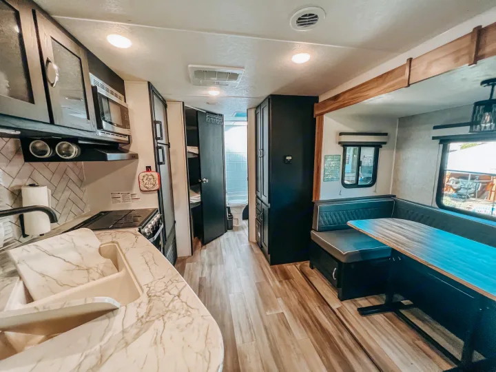 Spacious RV rental interior featuring a modern kitchen, cozy dining booth, and rear bathroom visible.. Coachmen 257BHS 2022