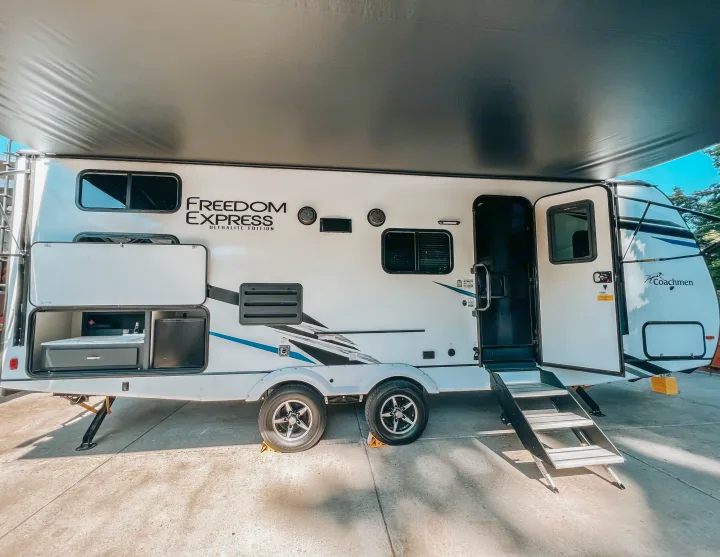 This Coachmen Freedom Express RV rental is ready for adventure with its outdoor kitchen, extended awning, and open door with steps.. Coachmen 257BHS 2022