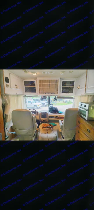 Cozy RV rental interior view from the living area, showing the cockpit, dog on dashboard, and overhead storage.. Fleetwood Other 2006