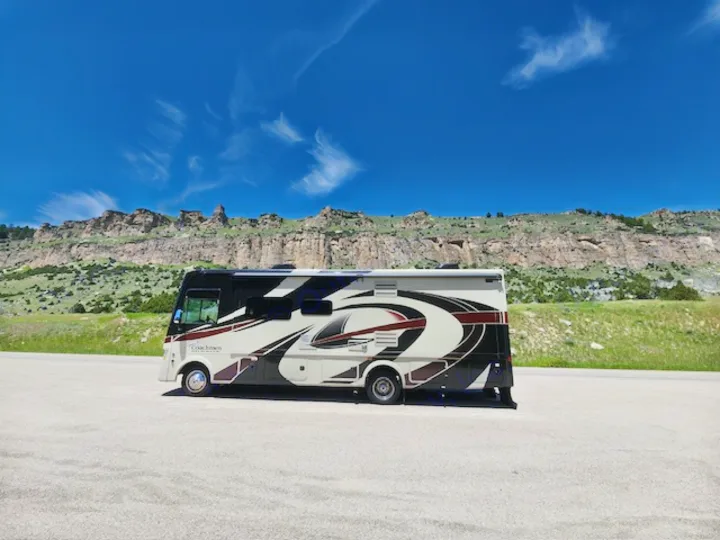 An RV rental, a Coachmen motorhome, parked against rocky mountains under a clear blue sky. Perfect for adventure!. Coachman Mirada 2018