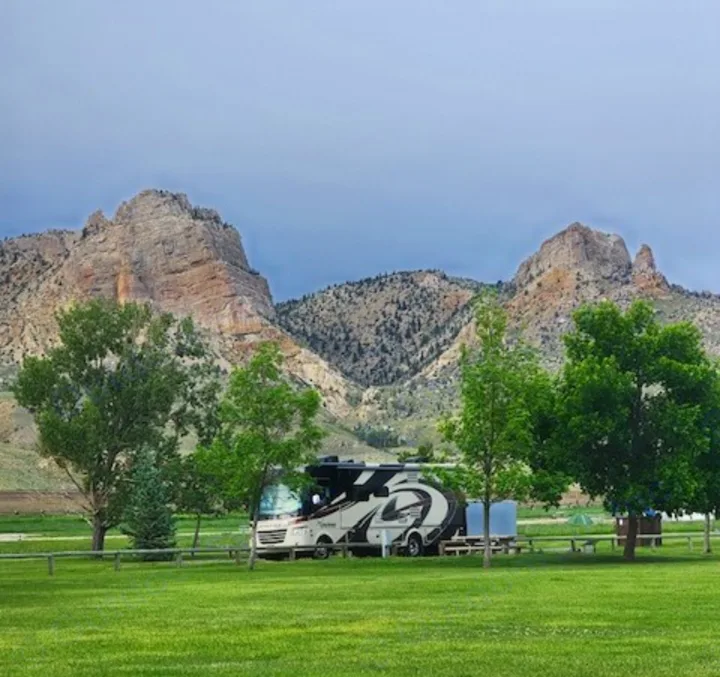 A scenic RV rental is parked on a lush green lawn with towering mountains in the background under a cloudy sky.. Coachman Mirada 2018