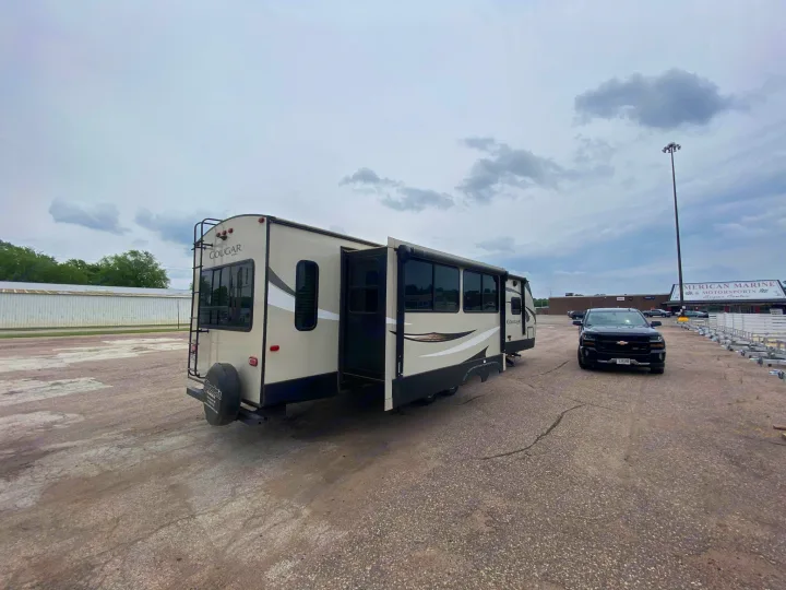 Cougar RV rental travel trailer with extended slide-out, parked with a truck in a spacious outdoor lot.. Keystone RV Cougar 2019