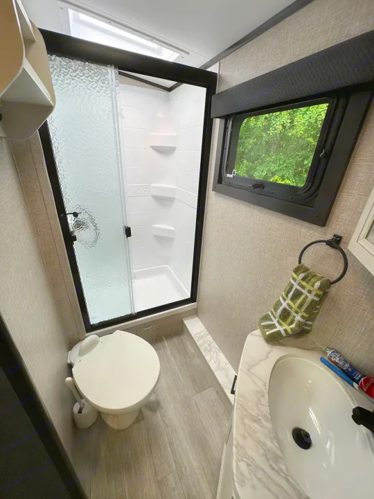 Experience comfort on the road in this rv rental bathroom, equipped with a shower, toilet, and vanity sink.. Jayco Whitehawk 2023