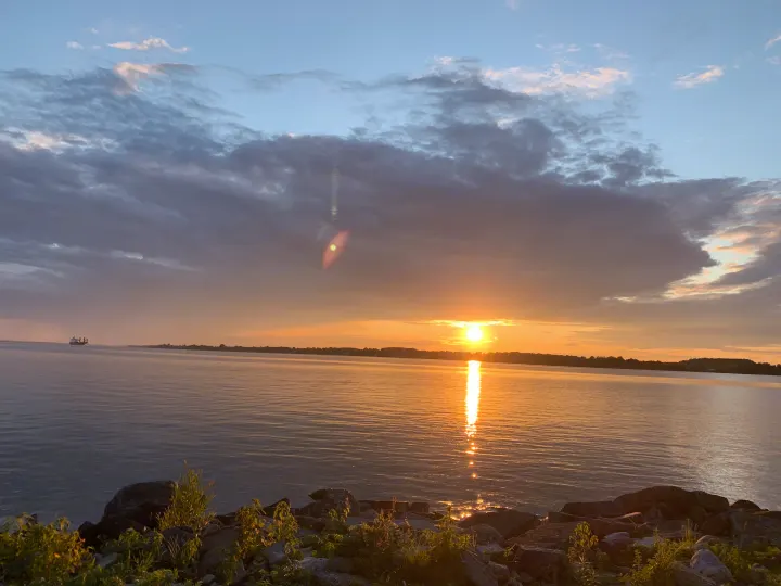 A serene sunset illuminates the water, with a distant ship and rocky shore. Perfect for an RV rental adventure.. Airstream Caraval 2021