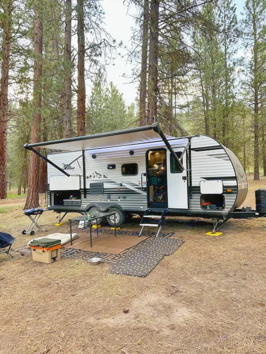 This comfortable rv rental is perfectly set up for camping in a pine forest, with an outdoor kitchen, cooler, and dog bed.. Jayco Jay Flight 2023