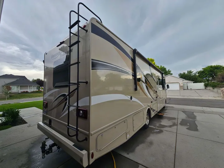 Beige Freedom Traveler RV, perfect for your next RV rental adventure, parked on a wet driveway.. Thor Freedom Traveler 2020