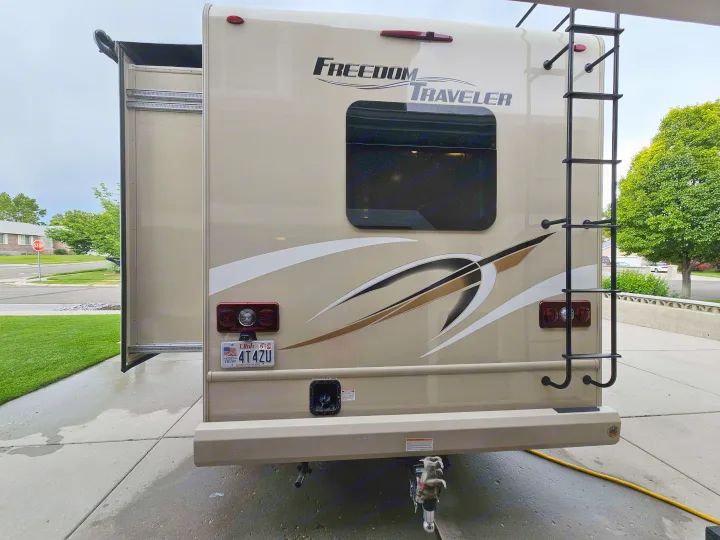 Back of a tan Freedom Traveler RV rental, showcasing an extended slide-out, rear ladder, and Utah license plate (4T4ZU).. Thor Freedom Traveler 2020