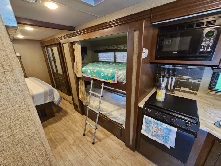 RV rental interior with bunk beds, a main bedroom, and a compact kitchen. Ideal for family trips.. Thor Freedom Traveler 2020