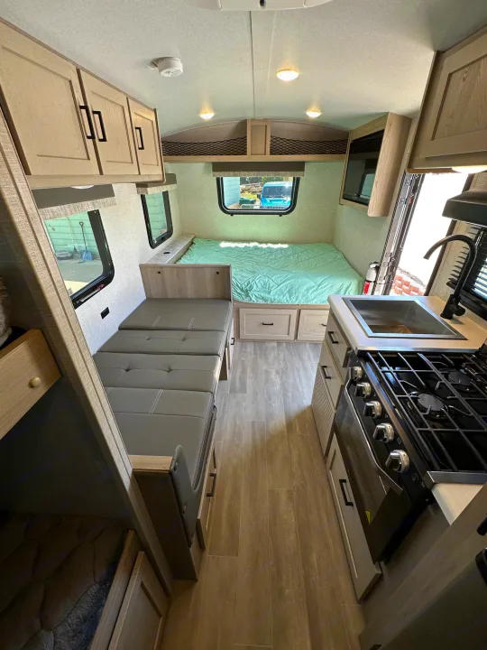 Clean, well-appointed RV rental interior: cozy bed, compact kitchen with sink/stove, and flexible dinette seating. Ready for adventure!. Forest River Flagstaff E-Pro 2023