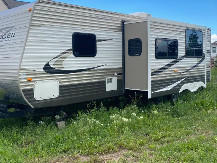 Explore the outdoors with this Zinger travel trailer RV rental. Its side is expanded on a grassy lot, perfect for camping.. Crossroads RV Zinger 2014