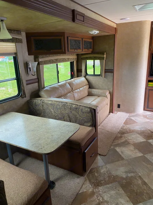 RV rental interior featuring a dinette, light-colored sofa, and wood-toned cabinetry. Comfortable, compact living area.. Crossroads RV Zinger 2014