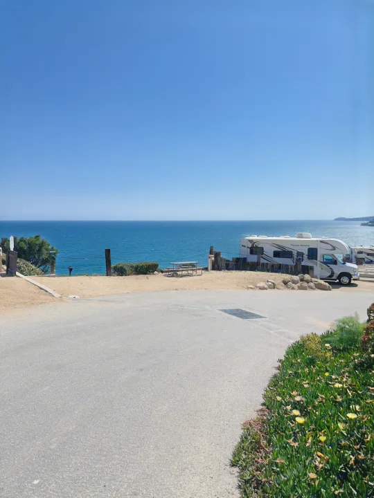RV rental parked at an oceanfront campground, featuring stunning sea views and clear skies.. Thor Four Winds 2020