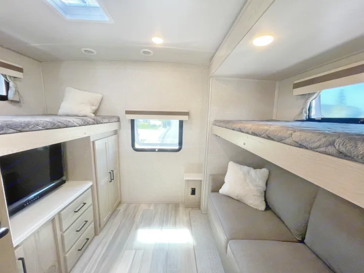 Cozy RV rental bunkhouse with upper beds, a sofa, TV, and ample storage. Ready for family adventures.. Forest River Rockwood Signature 2023