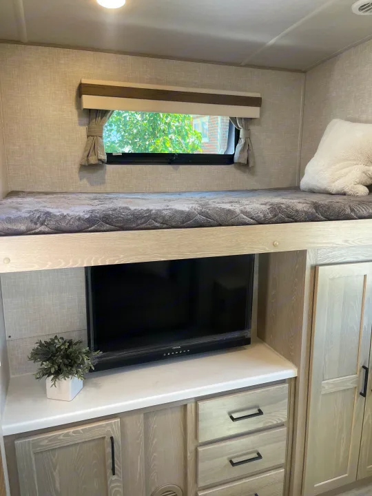 This modern RV rental features a comfortable bunk bed, built-in TV, and smart storage solutions for cozy travels.. Forest River Rockwood Signature 2023