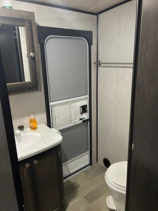 This RV rental features a compact bathroom with a sink, mirror, toilet, and towel bar, designed for space efficiency.. Heartland RVs Mallard 2020