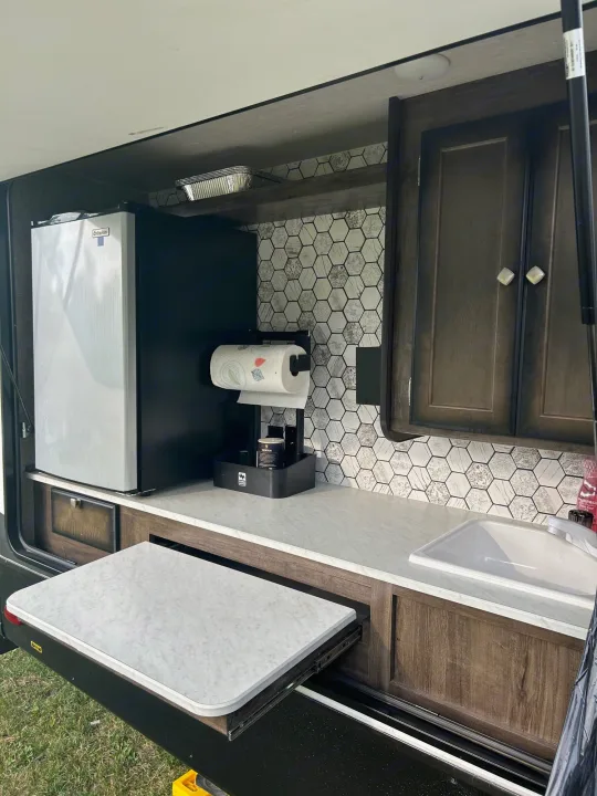 RV rental outdoor kitchen with fridge, sink, and pull-out table. Ideal compact camper cooking area.. Heartland RVs Mallard 2020