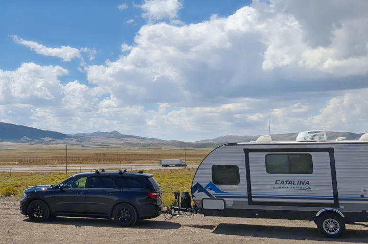 RV rental adventure: SUV towing a Catalina travel trailer at a scenic overlook with mountains & cloudy sky.. Coachmen Catalina Summit 184BHS 2022