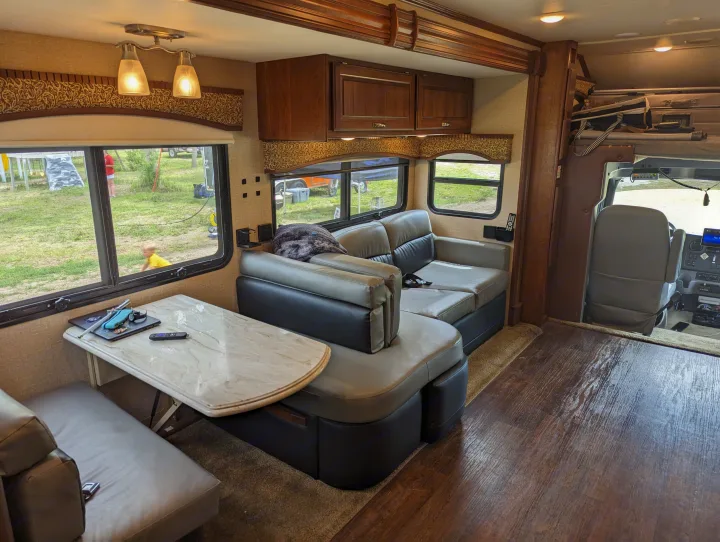 Spacious RV rental living area featuring a dining table, couch, storage, and clear views of the outdoors.. Dynamax Force 2015