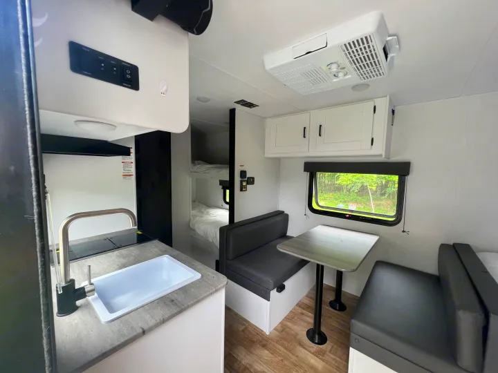 Interior of a modern RV rental, showing a kitchen, bunk beds, and dinette seating. Ideal for comfortable travel.. Keystone RV Hideout 2023