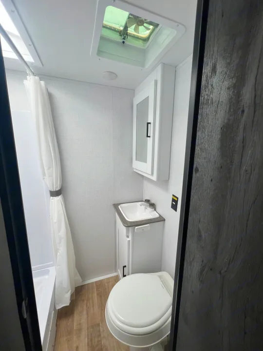 RV rental: A bright and clean bathroom featuring a shower, sink vanity, mirrored cabinet, and toilet for your travels.. Keystone RV Hideout 2023