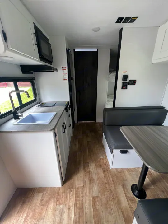 Modern RV rental interior with full kitchen, dinette, and bunk beds. Clean, bright space for your next adventure.. Keystone RV Hideout 2023