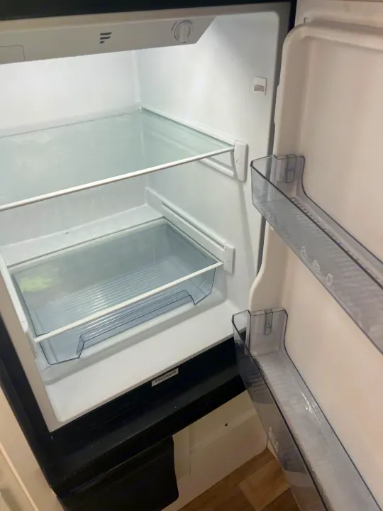 Empty & clean RV rental fridge, with glass shelves and crisper drawer, ready for your adventure.. Keystone RV Hideout 2023