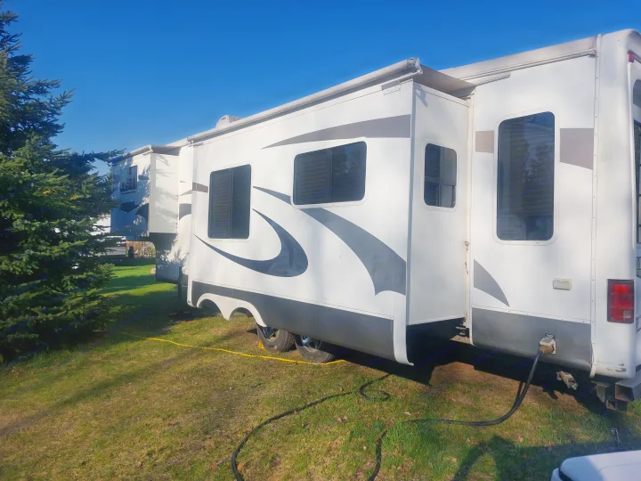 Side view of an RV rental on grass with slide-outs extended, powered up for a comfortable camping trip.. Crossroads Silverado 2005