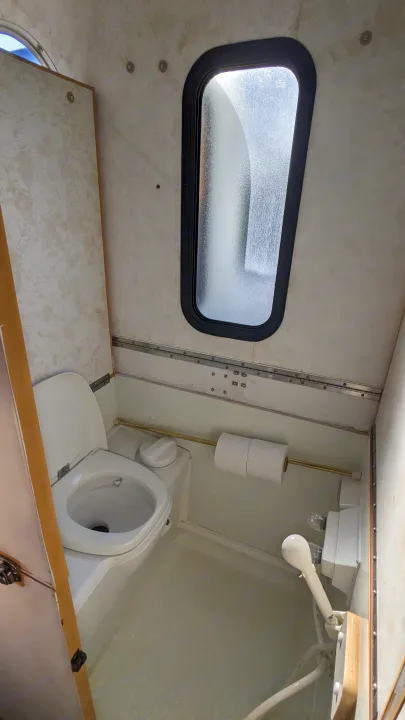 RV rental bathroom featuring a compact toilet, window, shower, and toilet paper holder.. Chalet Chalet Popup Trailer 2006
