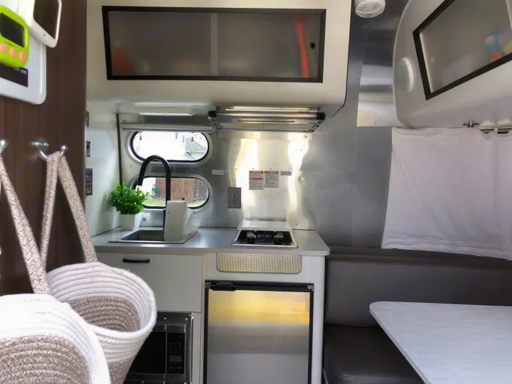 Experience RV rental comfort: a sleek, compact kitchen with dining area & built-in storage.. Airstream Caravel 2020