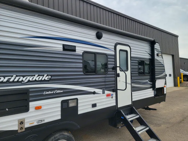Springdale travel trailer, gray/white/black with blue accent, ready for RV rental adventures. Steps lead to door.. Keystone 27BHS 2017