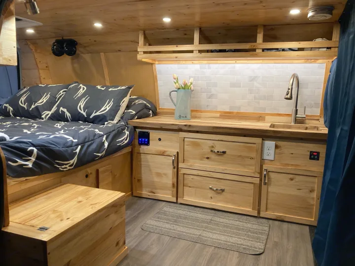 RV rental's inviting wood interior: comfy bed, kitchen with tile backsplash, sink, & smart storage for travel.. Gmc Savanna 2013