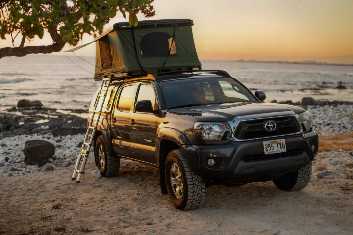 Experience RV rental adventure: A Tacoma truck with rooftop tent ready for beachside camping in Hawaii at sunset.. Other Other 2013