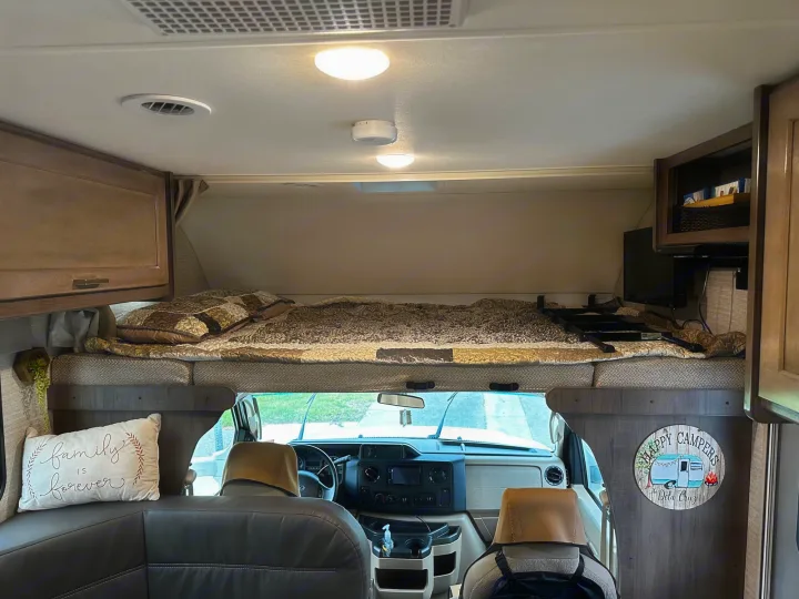Spacious RV rental interior featuring a cozy cab-over bunk bed, front cockpit, and a comfortable seating area.. Winnebago Minnie Winnie 2020