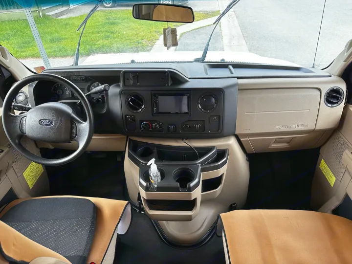 Front interior of an RV rental, highlighting the dashboard, Ford steering wheel, and organized center console.. Winnebago Minnie Winnie 2020