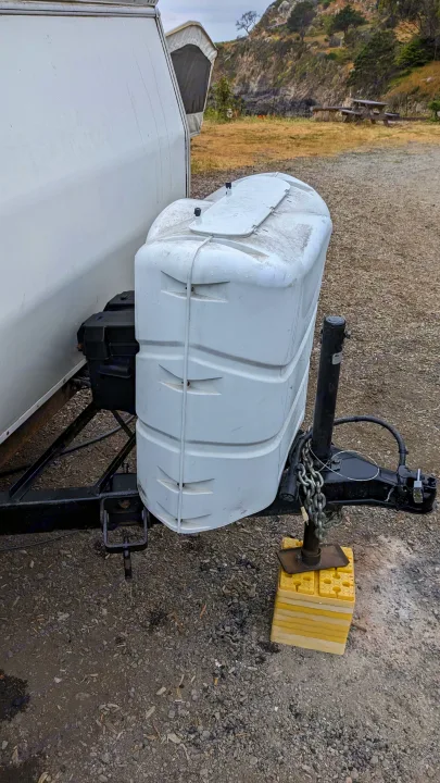 RV rental camper hitch area: white propane tank cover, black battery box, and jack on yellow leveling blocks.. Chalet Chalet Popup Trailer 2006
