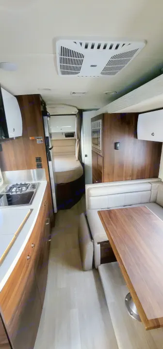 Modern RV rental interior: well-equipped kitchen with microwave/stove, plus comfy dining and seating area for travel.. Winnebago Navion 2022